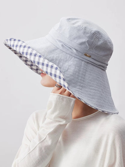 Woman wearing light blue cotton sun hat with wide brim, plaid lining, and soft foldable design
