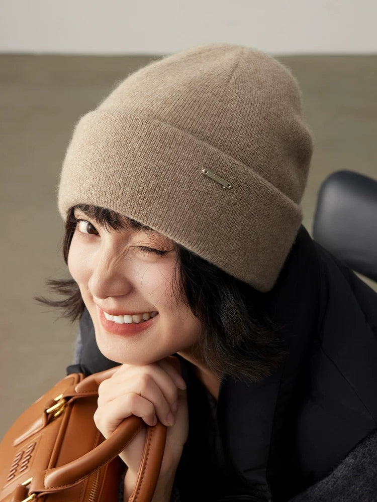 Smiling woman styling a light coffee pure cashmere beanie with a black winter coat