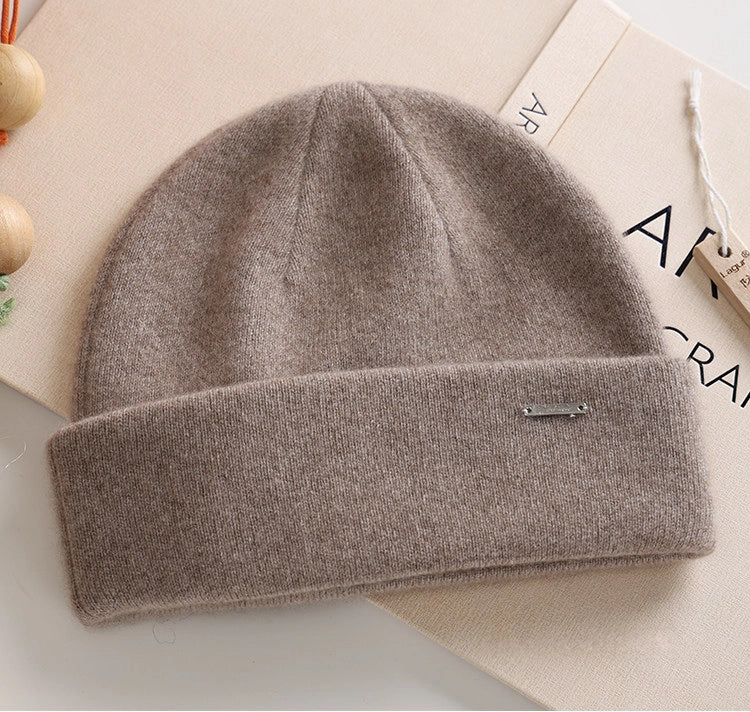 Light coffee 100% cashmere cuffed beanie with a small metal accent in a flat lay