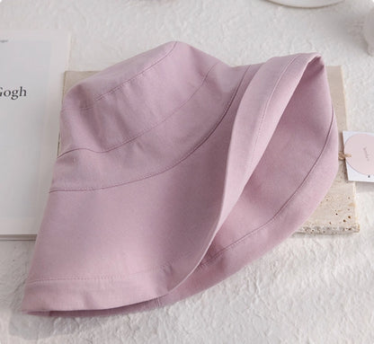 Close-up of a foldable light pink linen cotton sun hat showing its soft brim and fabric texture