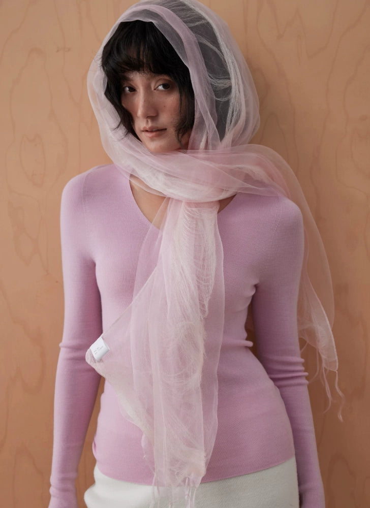 Woman wearing a lightweight pink silk fringe scarf loosely around her head and neck