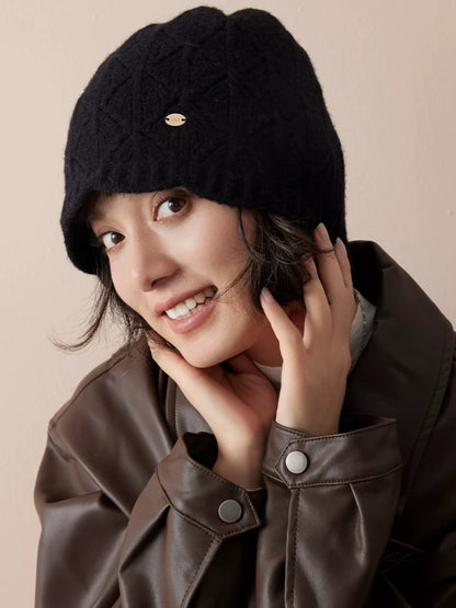 Close-up of a black wool knit beanie showing diamond pointelle texture and a ribbed edge.