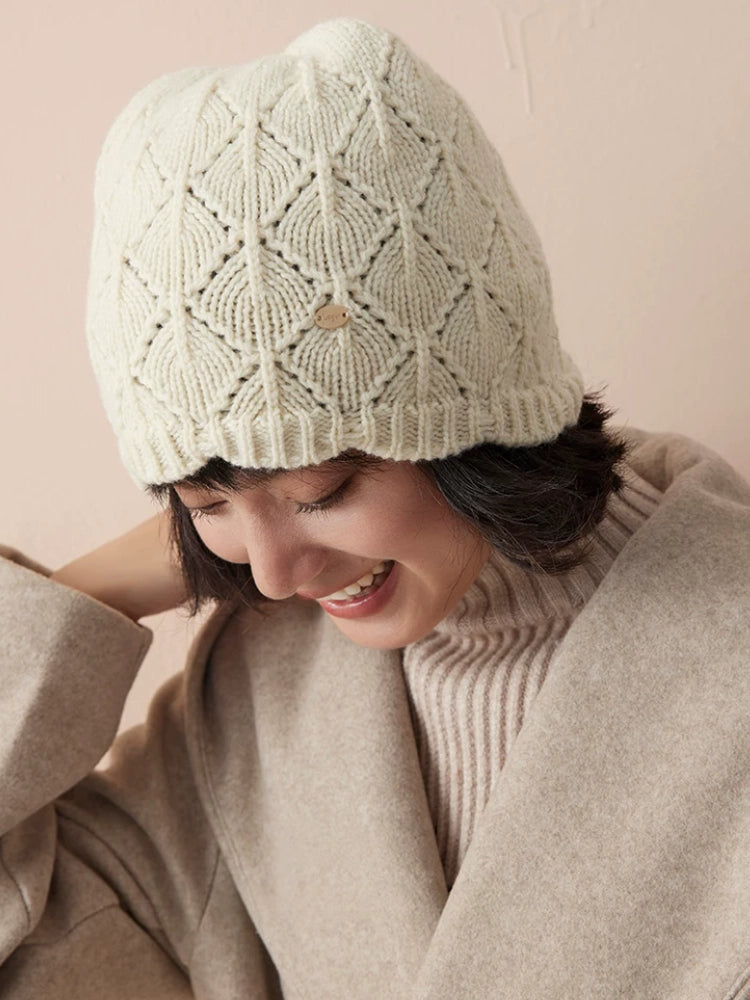 Cream-white wool beanie worn with the head tilted down, highlighting the diamond pointelle pattern.