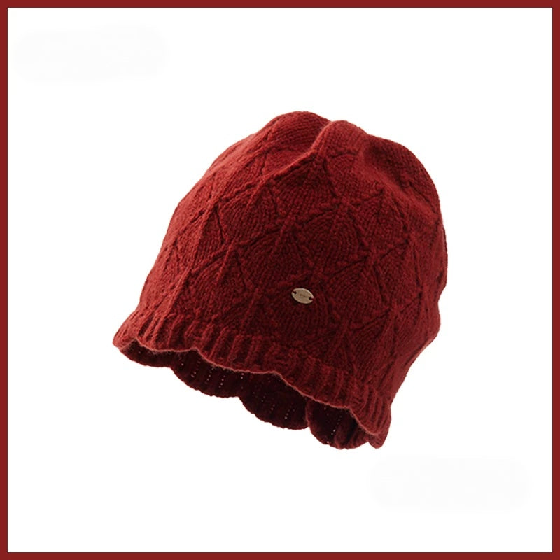 Red lightweight wool knit beanie with diamond pointelle detail, a scalloped edge and a gold-tone badge.