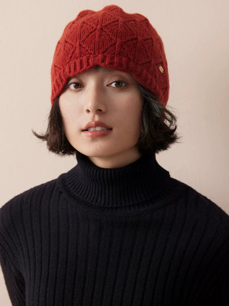 Front view of a model wearing a red wool pointelle beanie with a black turtleneck.