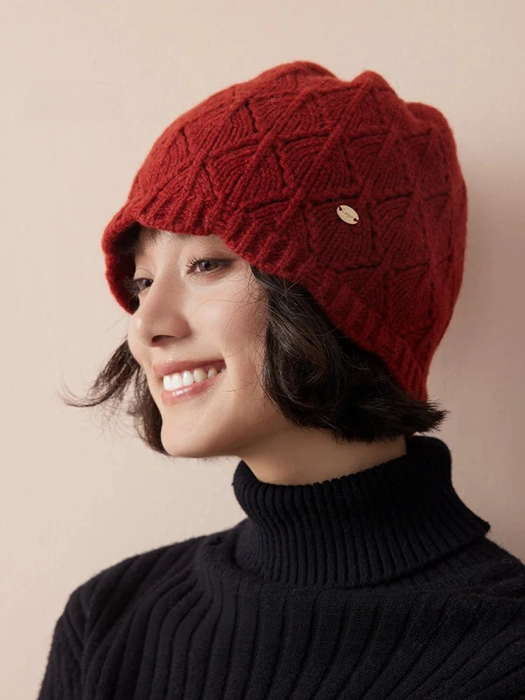 Three-quarter view of a red pointelle wool beanie, styled with short hair and a black turtleneck.