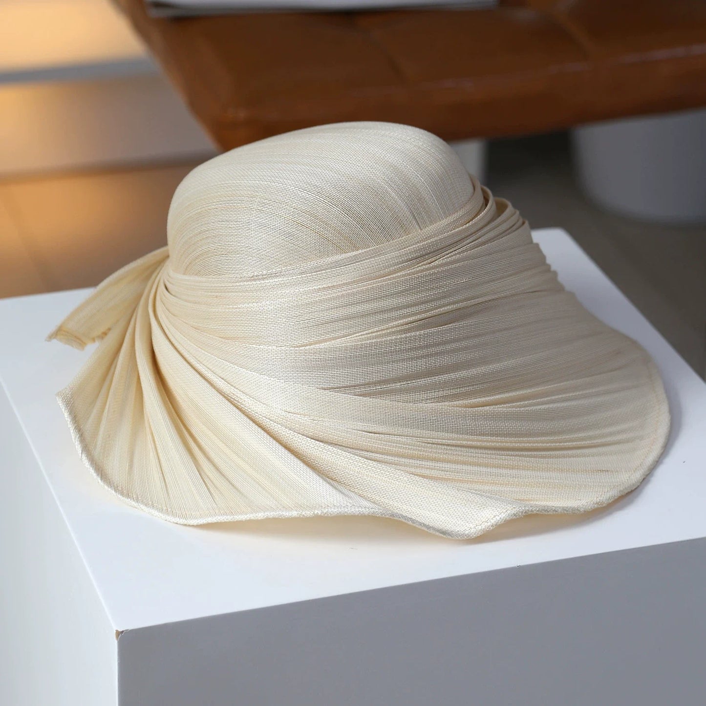 Ivory beige pleated Buntal straw wide brim hat with sculptural draped design.