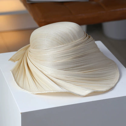 Ivory beige pleated Buntal straw wide brim hat with sculptural draped design.