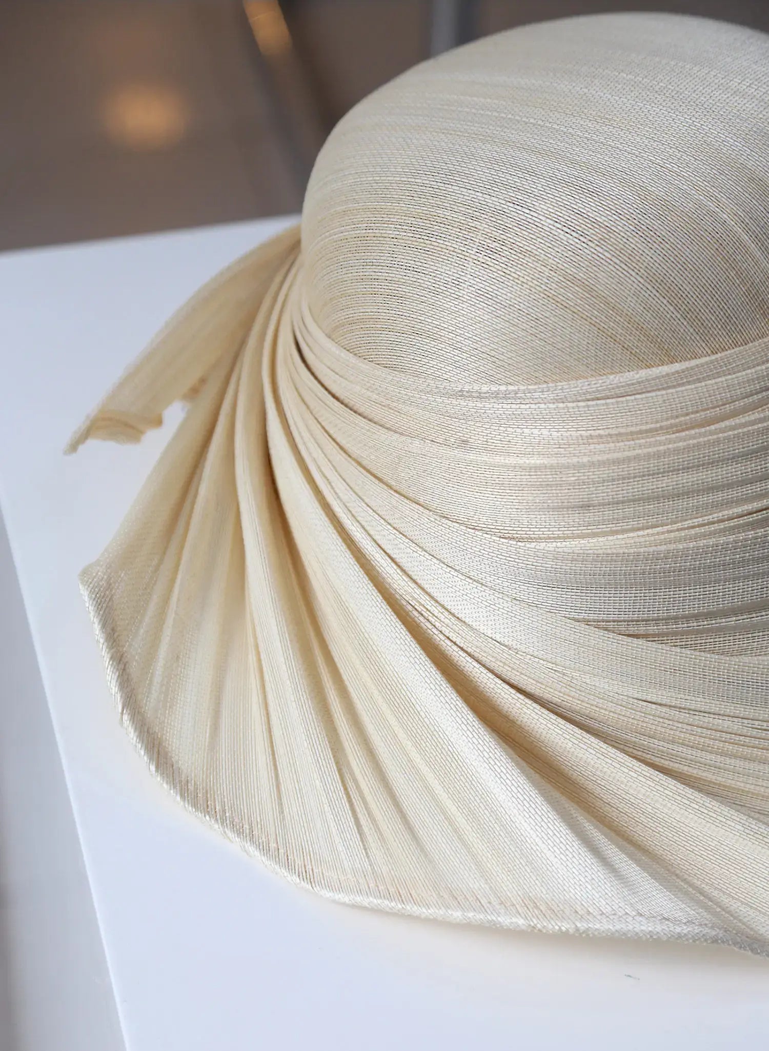 Close up of pleated Buntal straw wide brim hat in ivory beige.