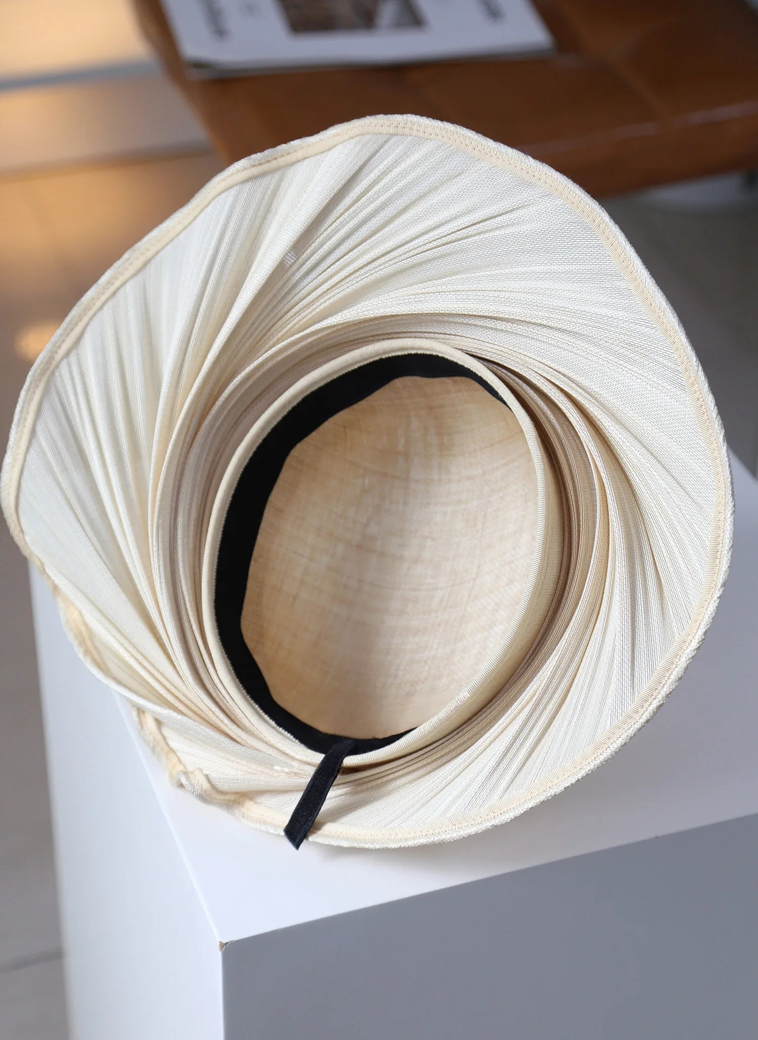 Top view of Buntal straw hat with adjustable strap and pleated wide brim.