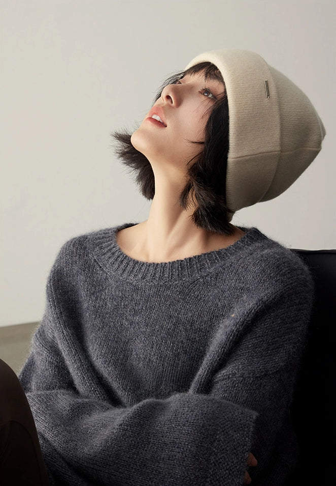 Side-profile woman wearing a milk white pure cashmere beanie with a charcoal knit sweater