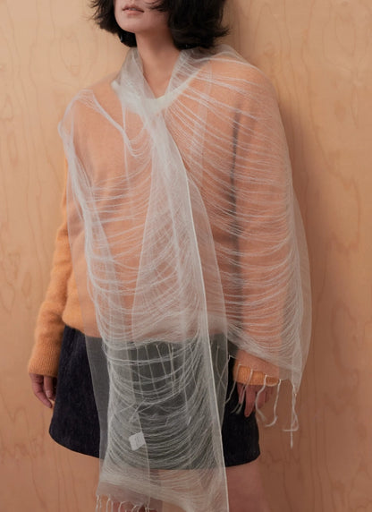 Woman styling a lightweight mist gray silk wrap with long flowing fringed ends
