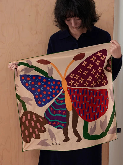 Woman holding an unfolded mulberry silk square scarf with a bold burgundy and blue butterfly print