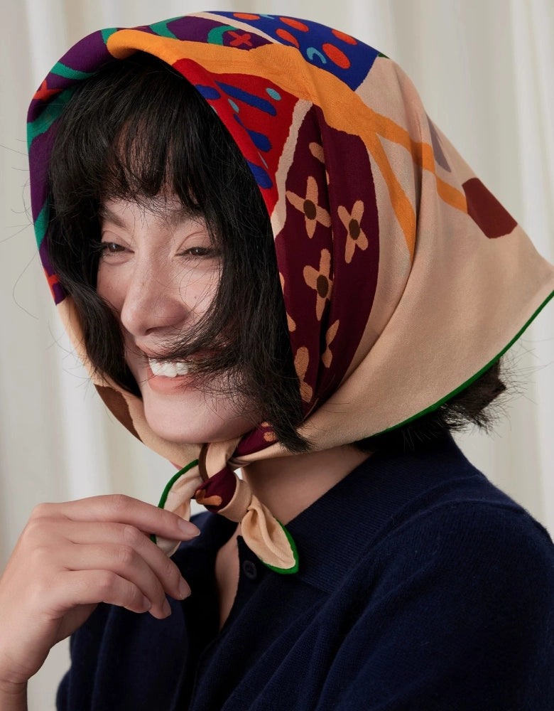 Woman styling a colorful butterfly print mulberry silk square scarf as a headscarf tied under the chin