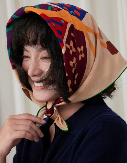 Woman styling a colorful butterfly print mulberry silk square scarf as a headscarf tied under the chin