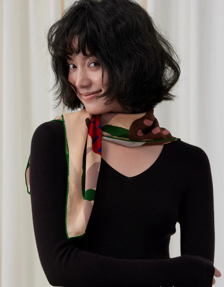 Woman wearing a graphic butterfly mulberry silk scarf as a slim neck tie with a black outfit