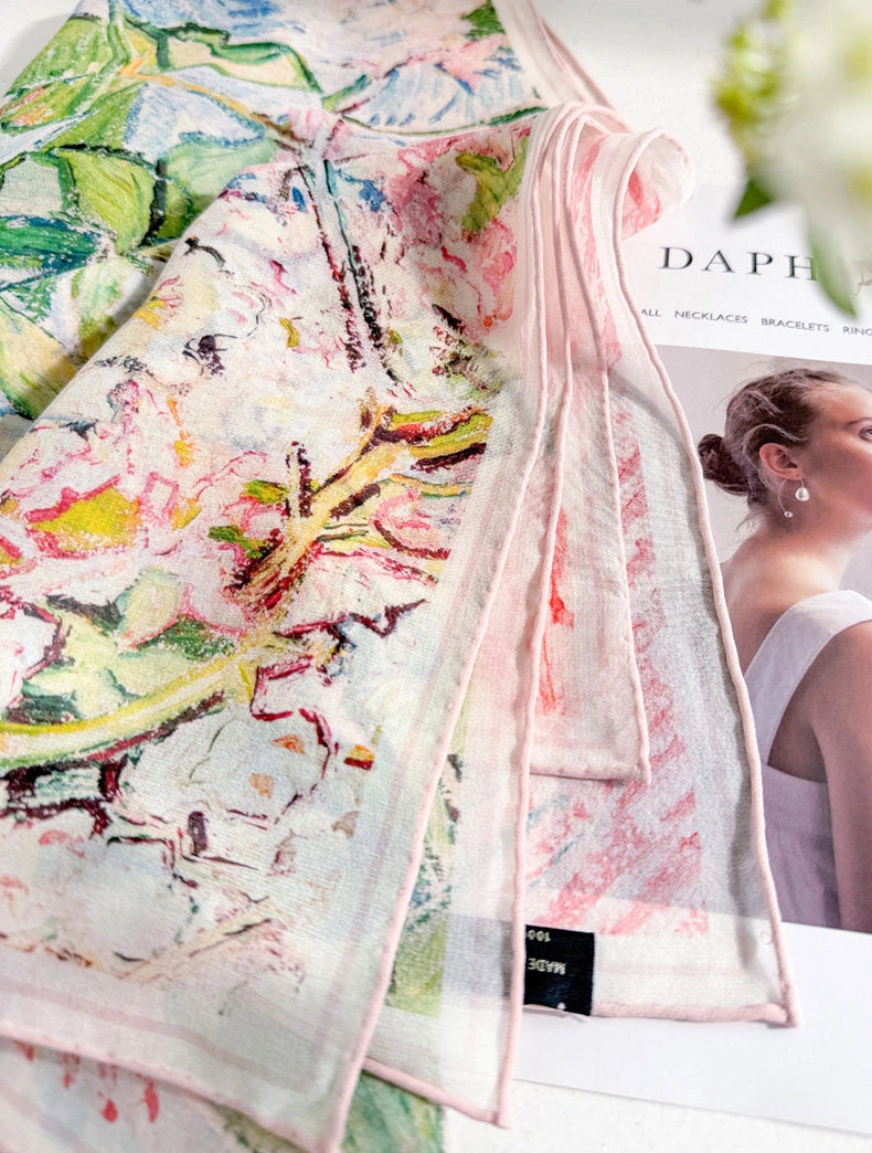 Detail of the artistic floral silk scarf print and translucent hem in pink, green, and blue tones