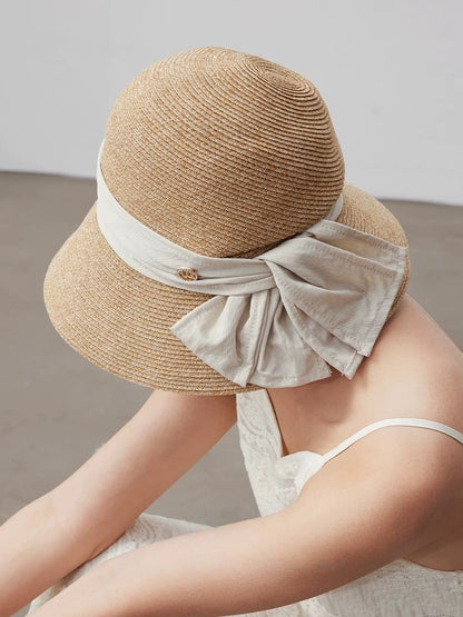 Moonlight white wide brim straw hat with soft bow ribbon, styled with a summer dress for refined vacation looks.