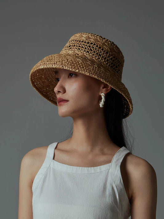Side view of woman wearing a wide-brim open-weave raffia sun hat