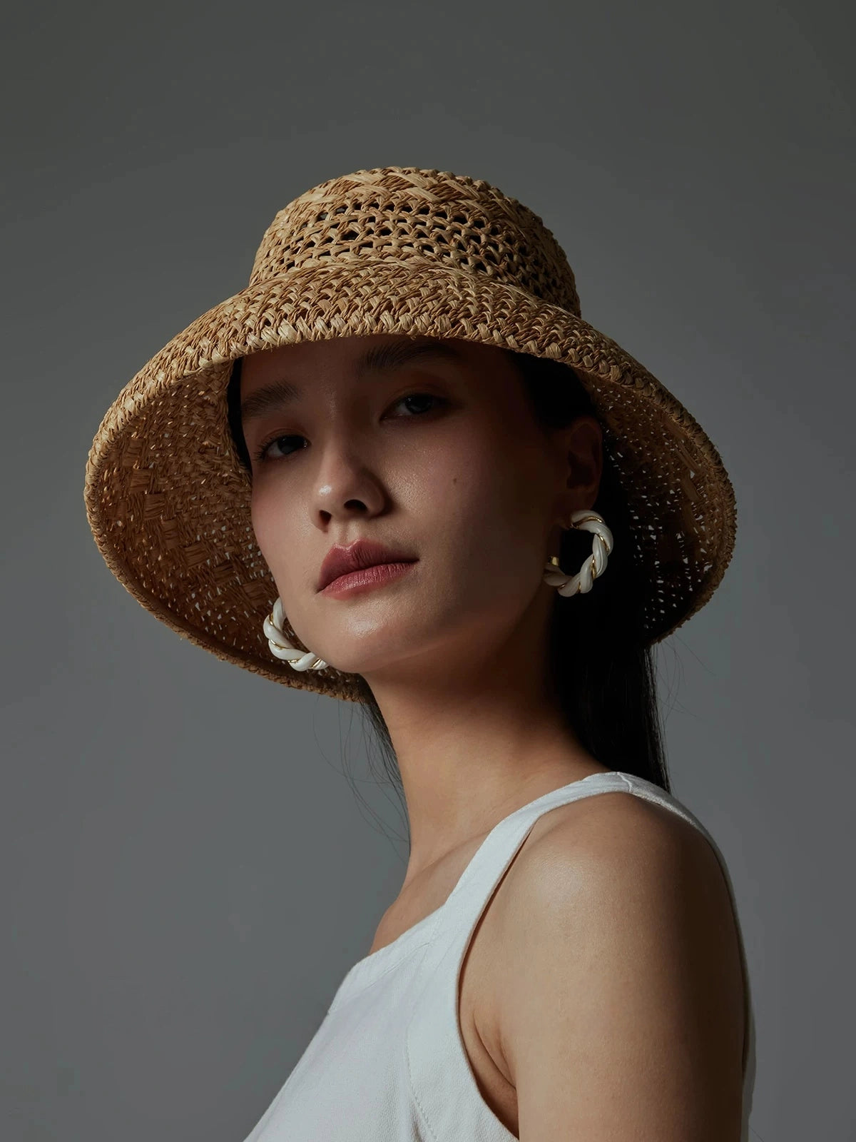 Woman modeling a natural raffia sun hat with breathable open-weave texture