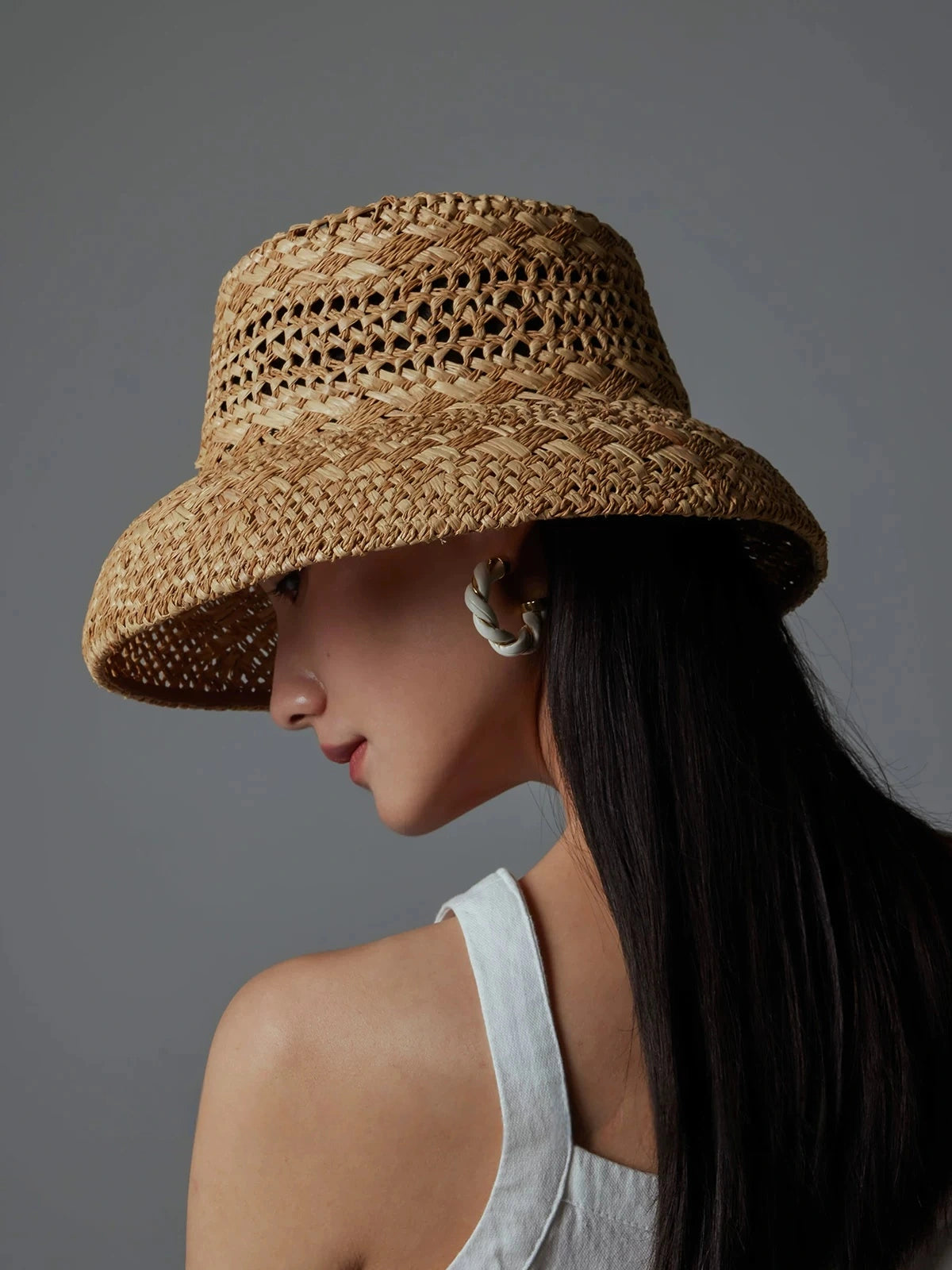 Back and side view of a wide-brim raffia sun hat showing the woven crown and curved brim