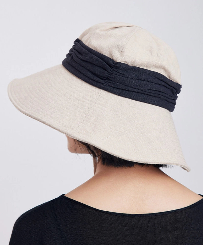 Back view of ivory beige foldable wide brim bucket hat with black contrast band and relaxed outdoor style.
