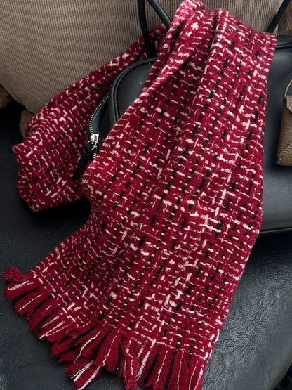 New Year red cashmere tweed scarf draped over a dark chair, highlighting its textured weave and long fringe.