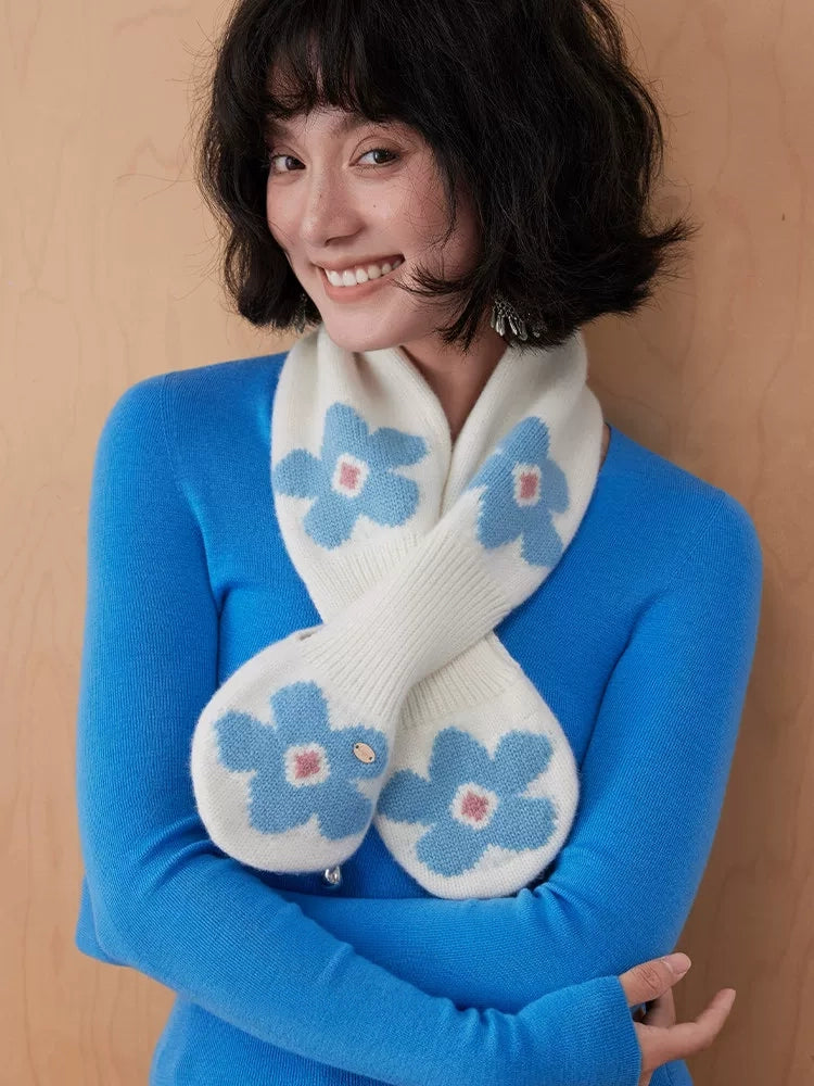Ivory wool keyhole scarf with blue flowers, worn crossed over a bright blue sweater.