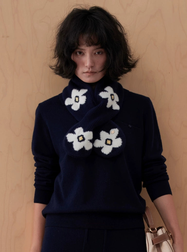Front view of a navy wool keyhole scarf with white flowers, styled with a navy sweater and a shoulder bag.