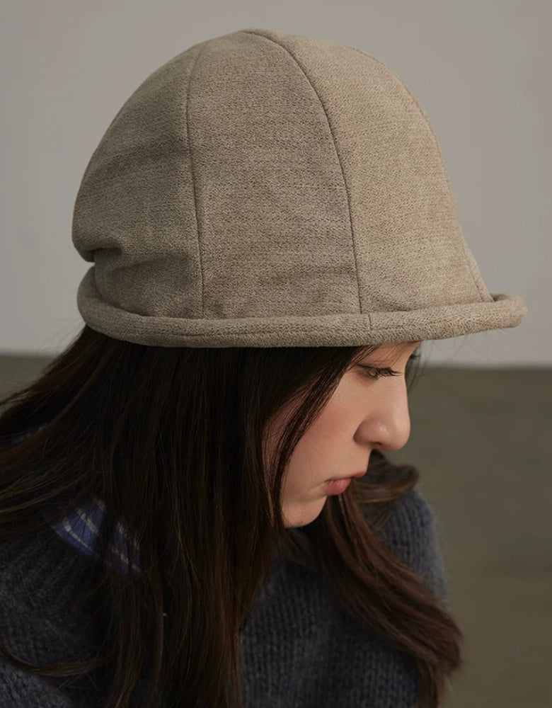 Close-up profile of a woman wearing an oatmeal greige vintage cloche hat with a curved brim