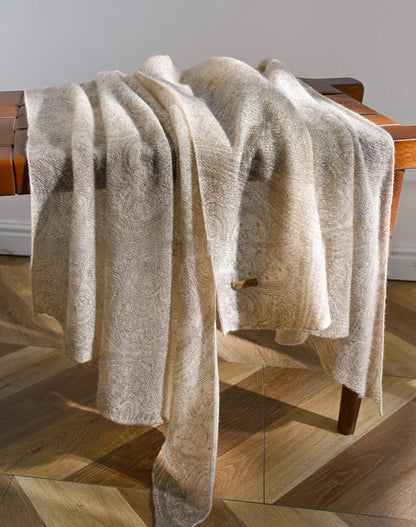Oatmeal lightweight cashmere scarf draped over a wooden chair, showing its length and flowing folds.