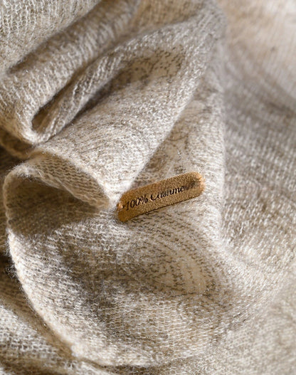 Oatmeal cashmere scarf fabric close-up showing its textured surface and 100% cashmere label.