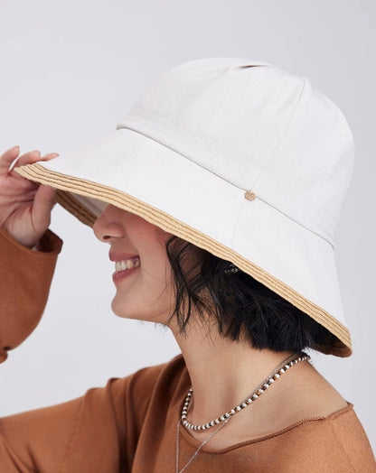 model adjusting an off-white wide brim sun hat for elegant resort and vacation styling