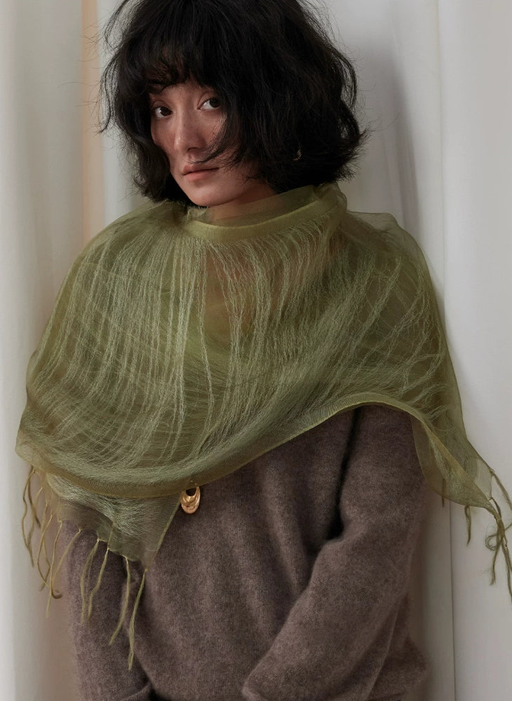 Sheer olive green silk fringe scarf draped softly across the shoulders