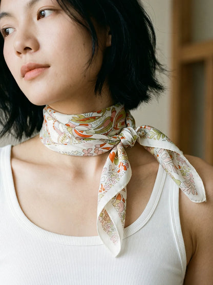 Woman wearing a pink beige elephant floral mulberry silk scarf in a layered neck wrap