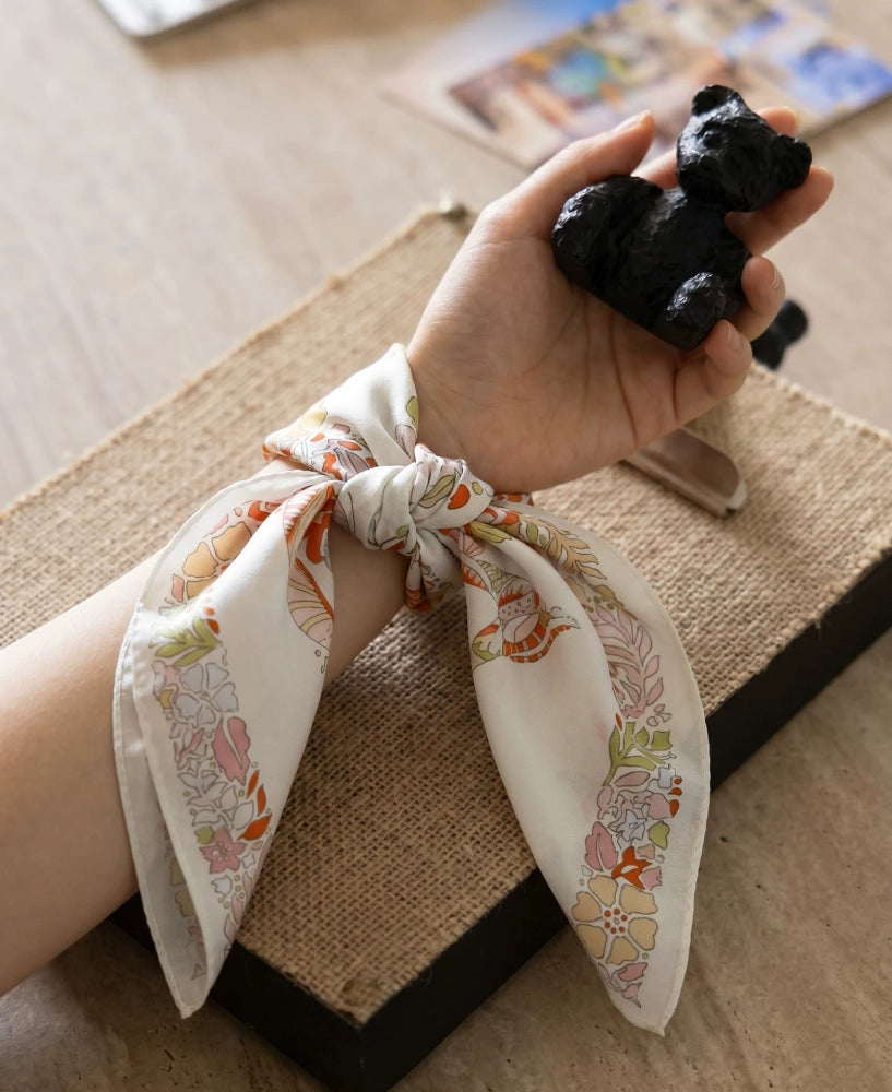Pink beige elephant floral silk scarf tied around the wrist as an elegant accessory