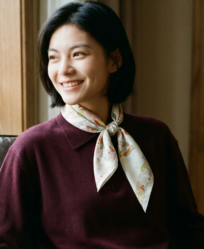 Woman styling a pink beige elephant floral silk scarf with a burgundy sweater