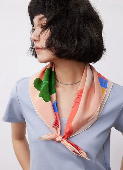 Pink mulberry silk square scarf styled around the neck with floral bird print