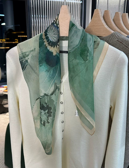 Plant-dyed gambier silk square scarf in green tone, worn on mannequin with elegant floral pattern