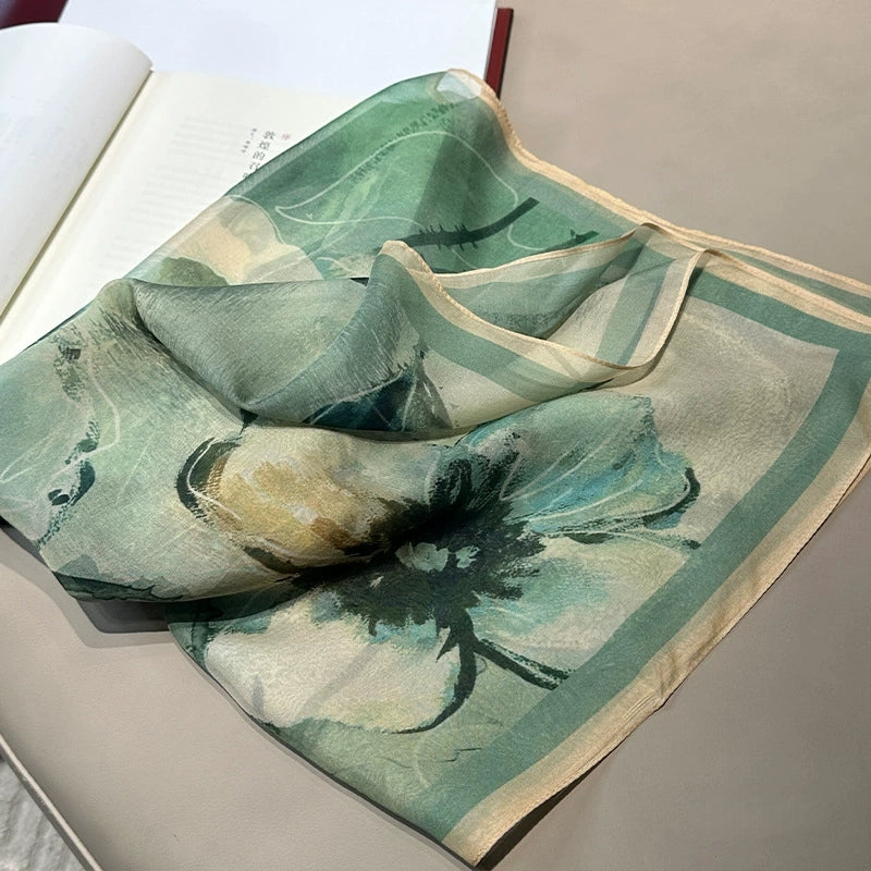 Close-up of mulberry silk scarf with soft green floral artwork, plant-dyed texture detail