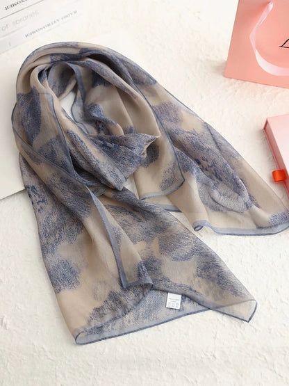 Plant-dyed mulberry silk long scarf in misty blue ink-wash pattern, folded on a light background