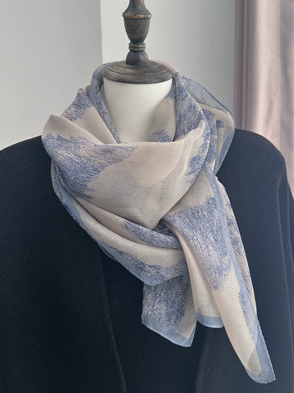 Misty blue mulberry silk scarf styled on a mannequin with elegant plant-dyed ink-wash design