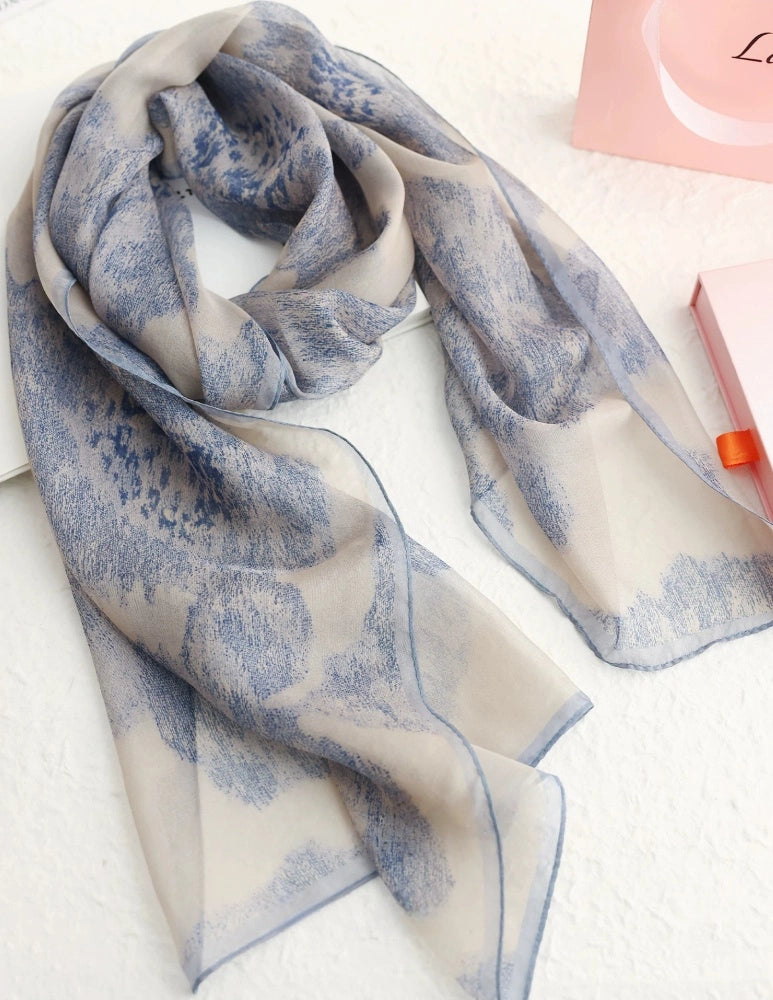 Close-up of long mulberry silk scarf with soft blue floral ink-wash pattern and airy texture