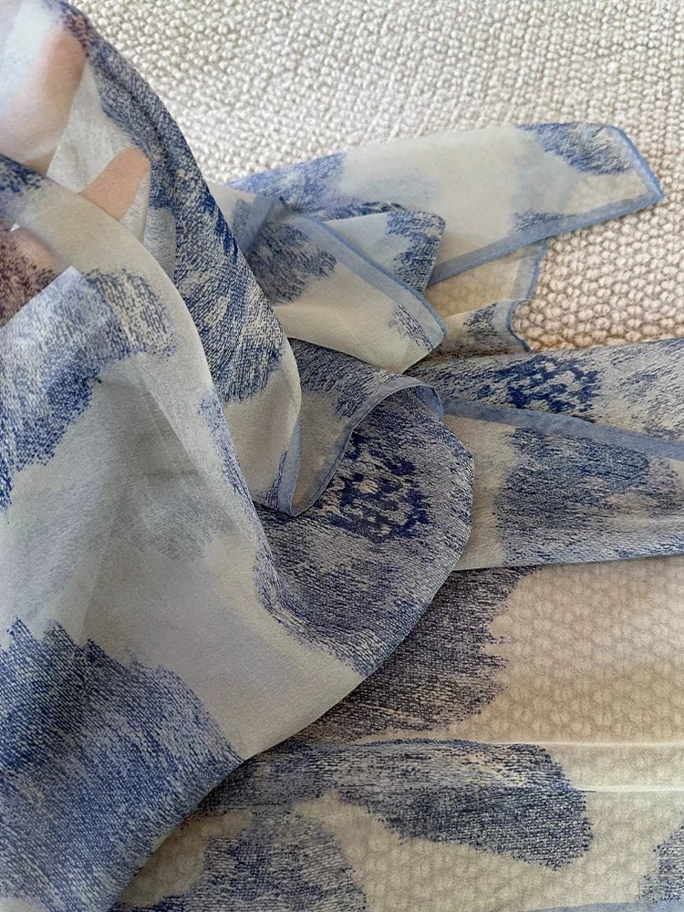 Detailed view of plant-dyed gambiered silk scarf with misty blue artistic print and sheer silk texture