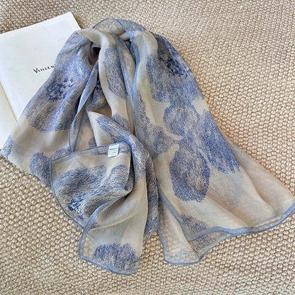 Long mulberry silk scarf in misty blue tones draped over a dark vest for elegant styling