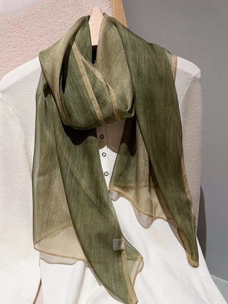 Light green plant-dyed long silk scarf styled over a white outfit for elegant layering