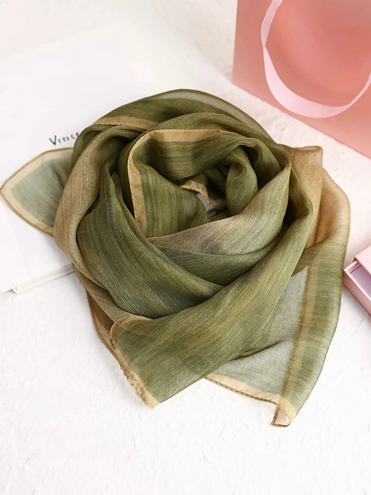 Light green mulberry silk scarf arranged in a soft circular drape with natural plant-dyed tones