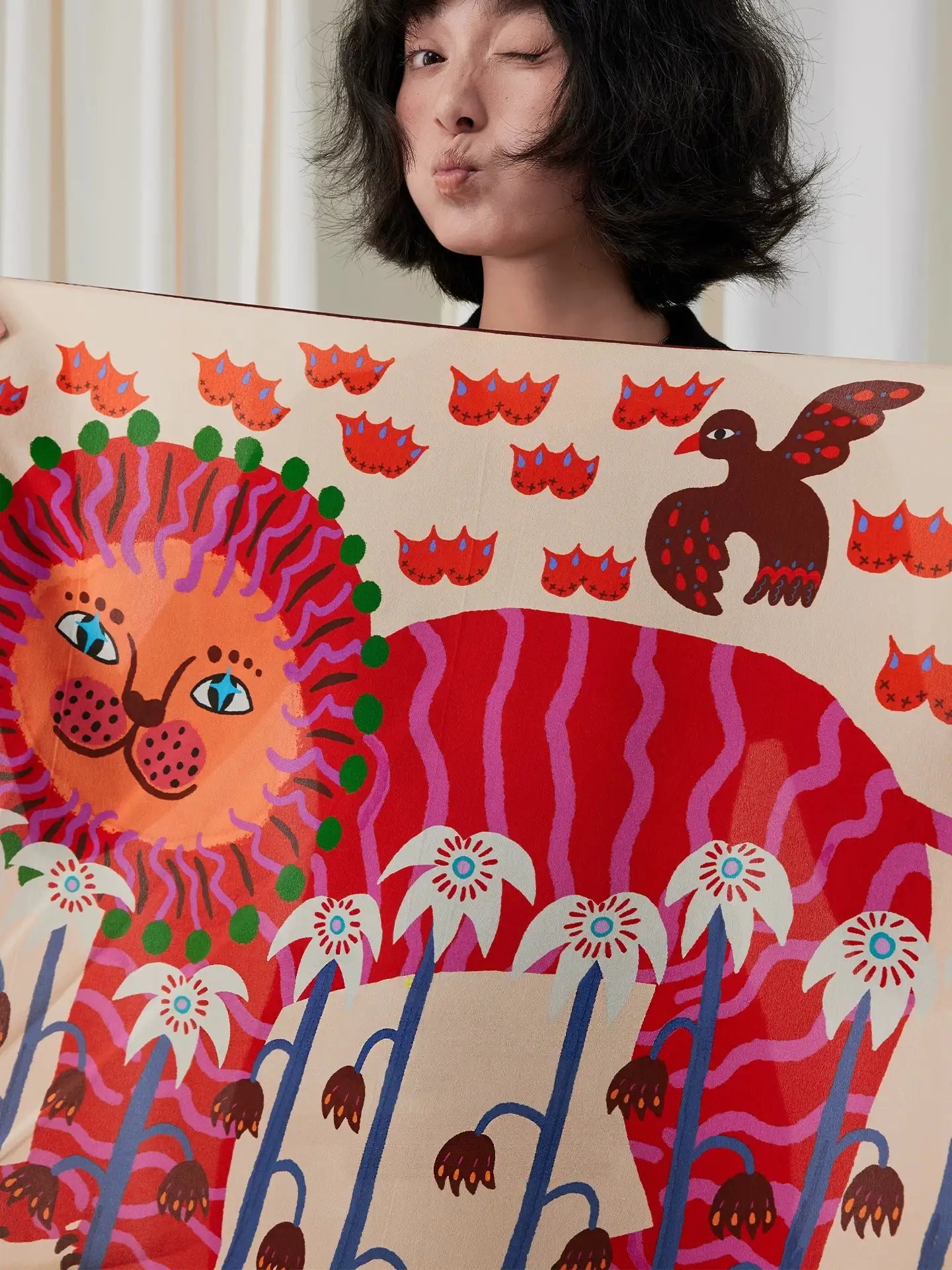 Woman holding an unfolded cream silk square scarf with a colorful folk lion and botanical print