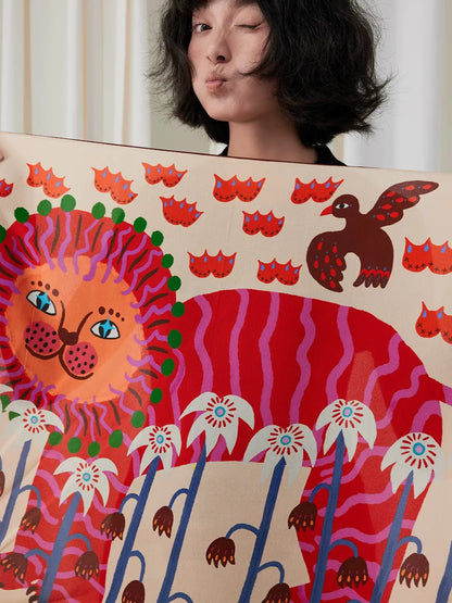 Woman holding an unfolded cream silk square scarf with a colorful folk lion and botanical print