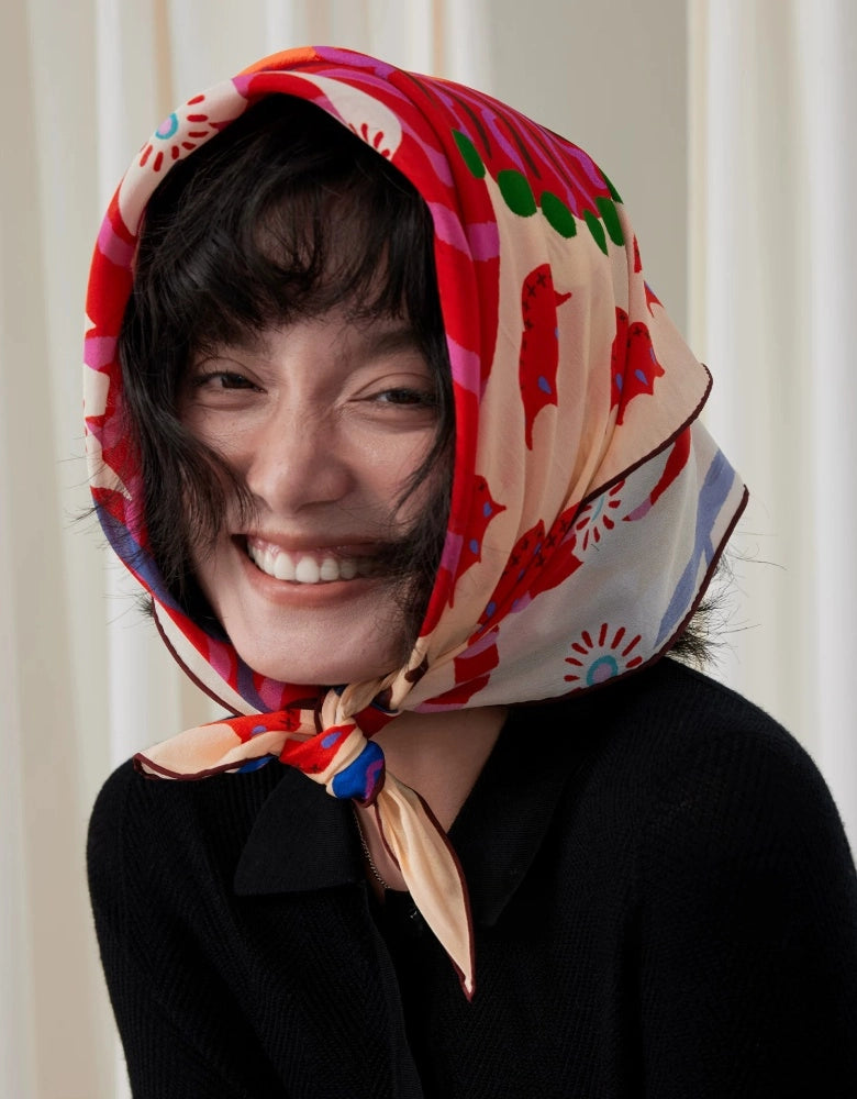 Smiling woman wearing a playful folk lion mulberry silk scarf tied beneath her chin